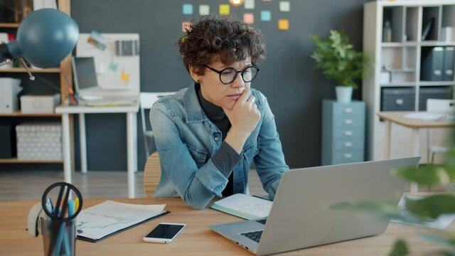 Stressed young woman is working on laptop then feeling headache touching head sitting at table in workplace. People, health and office stress concept.