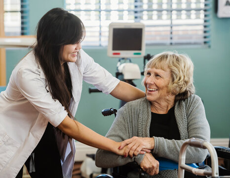 Nurse and senior woman holding hands in retirement home
