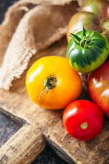 Fresh, ripe multi colored tomatoes on a dark background. Organic food.