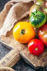 Fresh, ripe multi colored tomatoes on a dark background. Organic food.