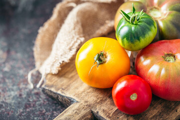 Fresh, ripe multi colored tomatoes on a dark background. Organic food.