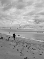 A lone fisherman on the ocean shore.