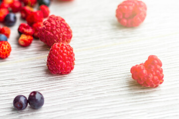 Wood background. Freshly picked blueberries, raspberries and wild strawberries.