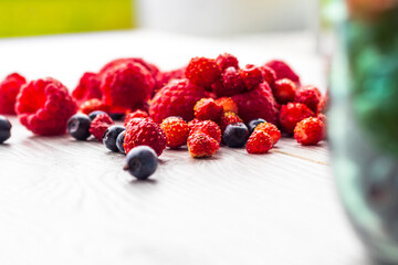 Wood background. Freshly picked blueberries, raspberries and wild strawberries.