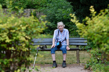 seniorin sitzt auf einer friedhofsbank