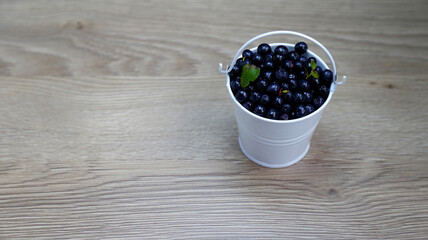 Fototapeta na wymiar bucket of American blueberries in a white bucket on a wooden table