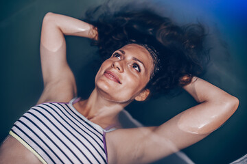 Beautiful pregnant woman floating in tank filled with dense salt water used in meditation, therapy, and alternative medicine.