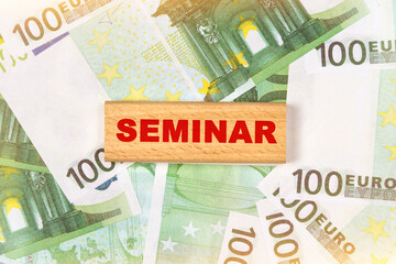 Against the background of euro bills, the text is written on wooden blocks - SEMINAR