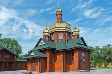 Fototapeta na wymiar Small log church with three gilded domes