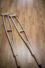 Wooden crutches on a wooden floor, for the movement of people with disabilities, people with fractures and sprains, or bone defects.