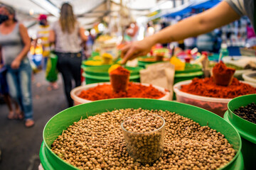 Barraca de especiarias na feira de rua de São Paulo com pessoas desfocadas ao fundo