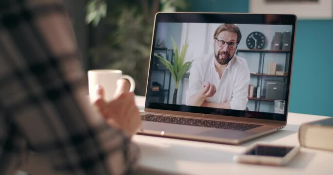 View of computer screen with bearded man in white shirt discussing common project with female coworker on video call. Woman staying at home and solving working issues on distance.
