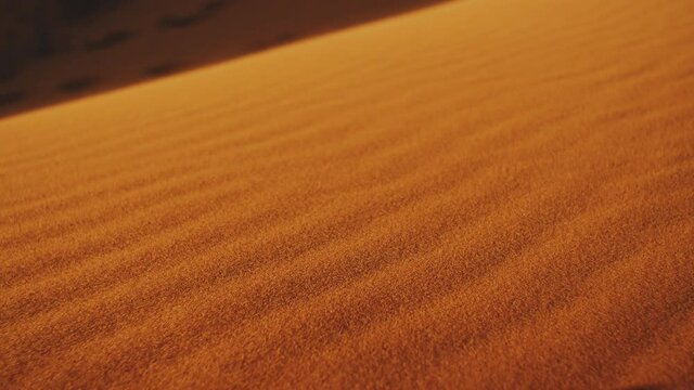 Close-up of wind blows sand in the desert of sand dunes in the Sahara desert at sunset, sun bunnies into camera, 4k