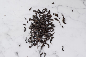 Leaves of black tea lie on the marble table