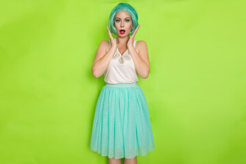Portrait of a beautiful young woman with short blue hair in a studio on a green background