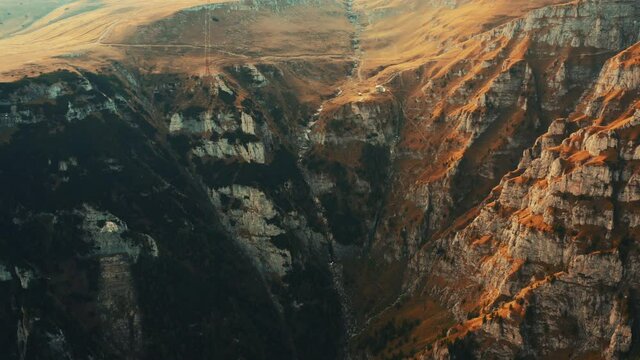 Aerial view on rocky peak mountains. Video from drone flying over valleys, forested and cliffs slopes of the mountain range. Sunset time in Romania, Majestic landscape, travel background, 4k
