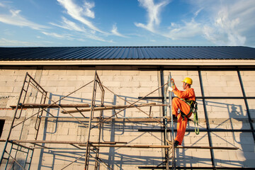 Naklejka premium Workers wear protective clothing Roof construction, new roof installation, roofing tools, electric drill used on new roofs with sheet metal construction