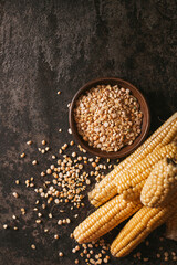 Ripe corn with pea seed on dark background.