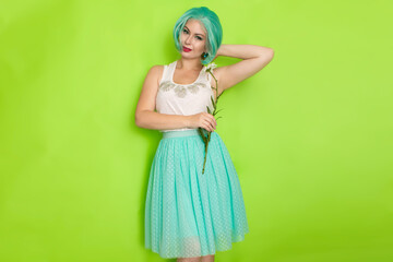Studio portrait of beautiful mint hair feminine in white top and light blue skirt holding big...