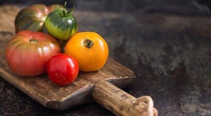 Fresh, ripe multi colored tomatoes on a dark background. Organic food.