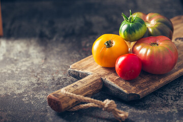 Fresh, ripe multi colored tomatoes on a dark background. Organic food.