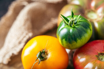 Fresh, ripe multi colored tomatoes on a dark background. Organic food.