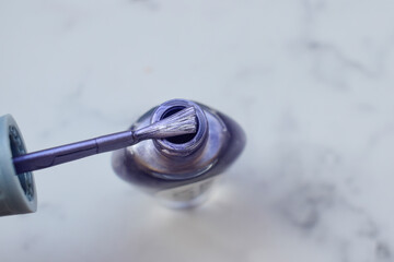 Obraz premium Nail Polish is purple with a metallic tinge. Brush is wiped on a jar of nail Polish, manicure tool