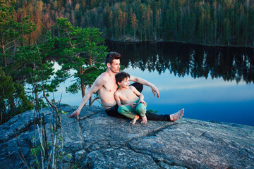 Fototapeta premium middle age man with little cute son doing sport yoga on the top of the mountain together, happy family lifestyle people outdoor, summer wild nature for training