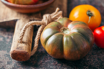 Fresh, ripe multi colored tomatoes on a dark background. Organic food.