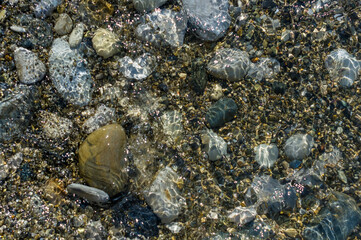 pebble stones on the sea beach, the rolling waves of the sea with foam