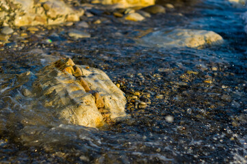 pebble stones on the sea beach, the rolling waves of the sea with foam