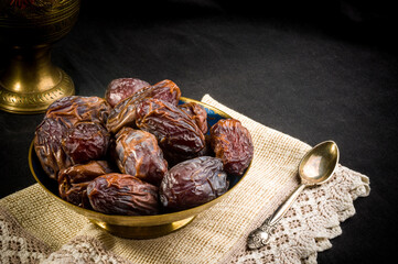 Big luxury dried date fruit in bowls on a linen napkin, kurma ramadan kareem concept, close up.