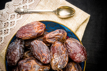 Big luxury dried date fruit in bowls on a linen napkin, kurma ramadan kareem concept, close up.