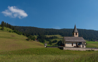 Fototapeta na wymiar South Tyrolean mountain church under a blue sky with a single white cloud