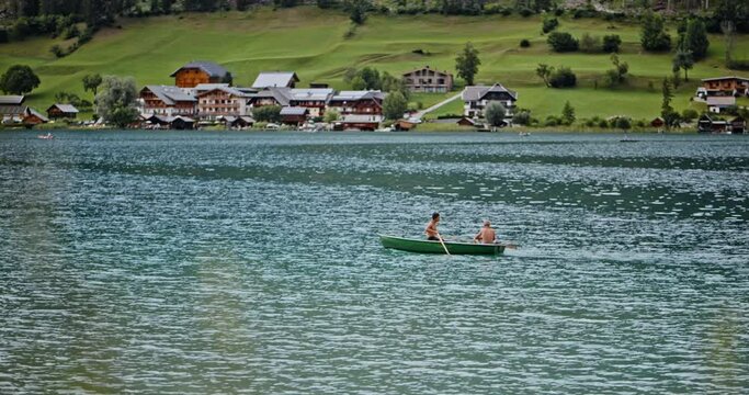 People boating on the river. Two men advanture on the boat. Spending vacation outdoor in summer. One man is paddling the vessel and another is fishing. Concept of tourism, active travel, sport.
