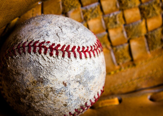 Badly damaged old baseball with texture of baseball glove closeup.