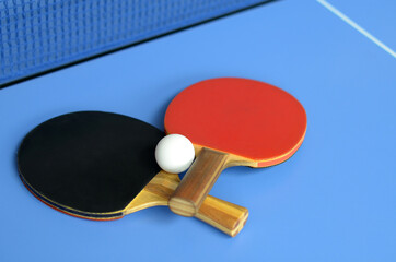 Red and black Table Tennis Paddles and ball on the blue table
