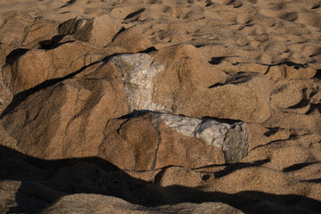 Sandstone rocks on beach with stripe of white igneous rock through the middle