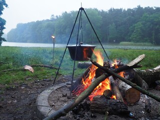 A torch, a bonfire and a hanging pot by the lake on the Summer solstice day (Szczecin, Poland)
