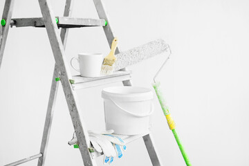 Tools for painting walls: roller, tray, bucket of paint, brush, gloves and a cup of coffee on a...