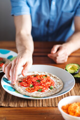 Man grabbing a homemade pizza with tomatoes