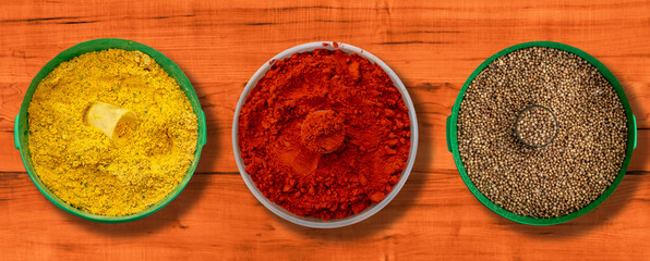 Mesa de madeira com temperos e especiarias para culinária( Colorau, Pimenta Branca e Caril).
