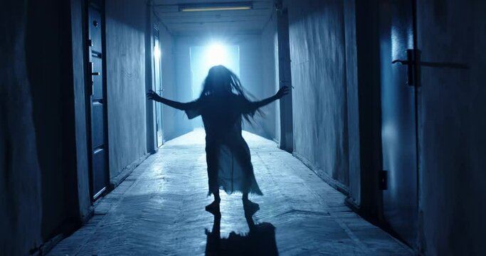 Little girl in white dress looking like a ghost carelessly running down the hallway of a haunted house - halloween costume party, horror movie 4k footage