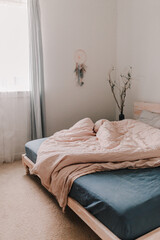 Cozy light and bright bedroom. Bed linen. White, beige, grey, blue. Wooden bed frame. Apartment living. Minimalist lifestyle. Empty walls. Early morning light. King size bed. Modern interior.