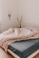 Cozy light and bright bedroom. Bed linen. White, beige, grey, blue. Wooden bed frame. Apartment living. Minimalist lifestyle. Empty walls. Early morning light. King size bed. Modern interior.
