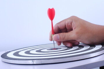 Hand gold red dart arrow hitting in the target center of dartboard