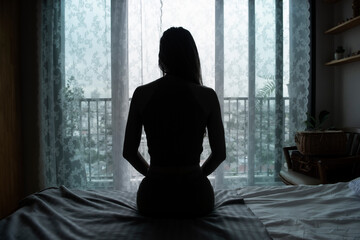 silhouette of a young woman sitting on a bed