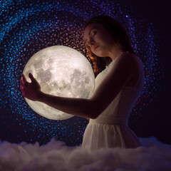 Naklejka premium Delicate photography, Astrology, Women's magic. Beautiful attractive girl on the background of the universe and the stars hugs the moon in the clouds, art photography, femininity