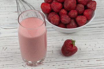 strawberry cocktail, blender and plate with strawberries on a white wooden background