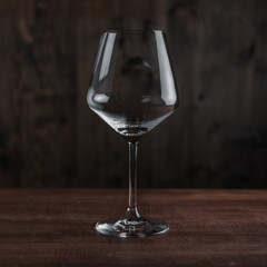 Empty wine glass on wooden table against dark background in bar. Catering Concept